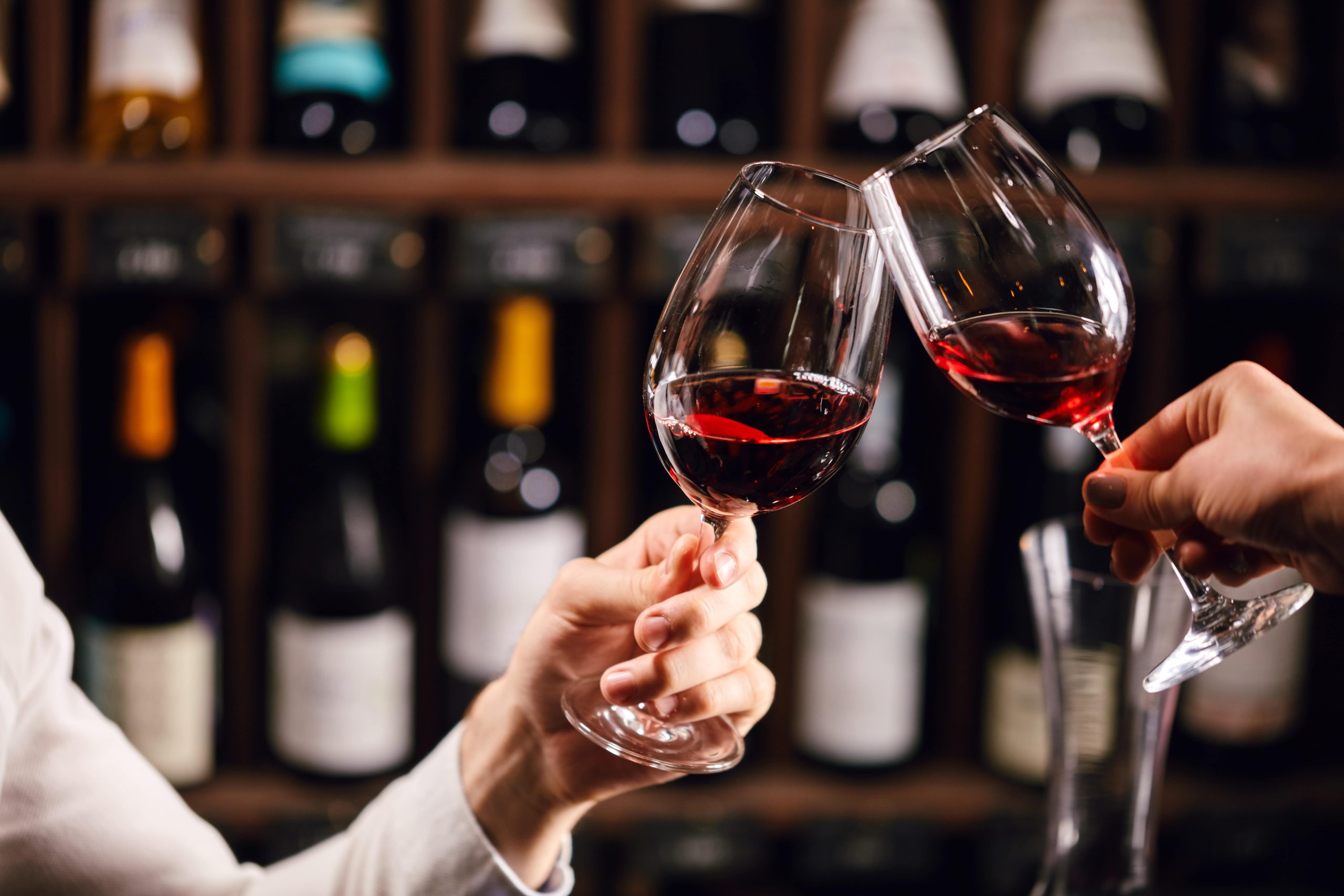 two people clinking their wine glasses together.