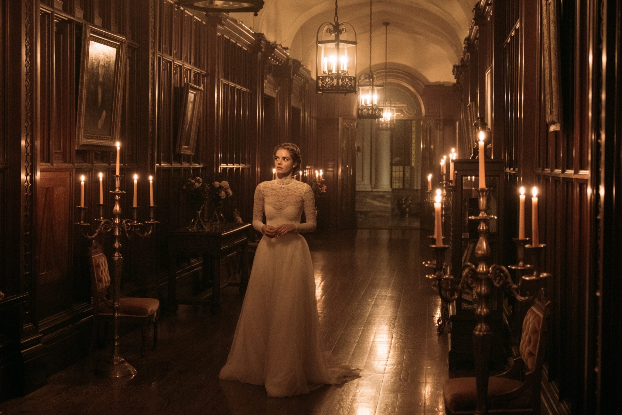 Lady walking through a hallway lit up by candles.