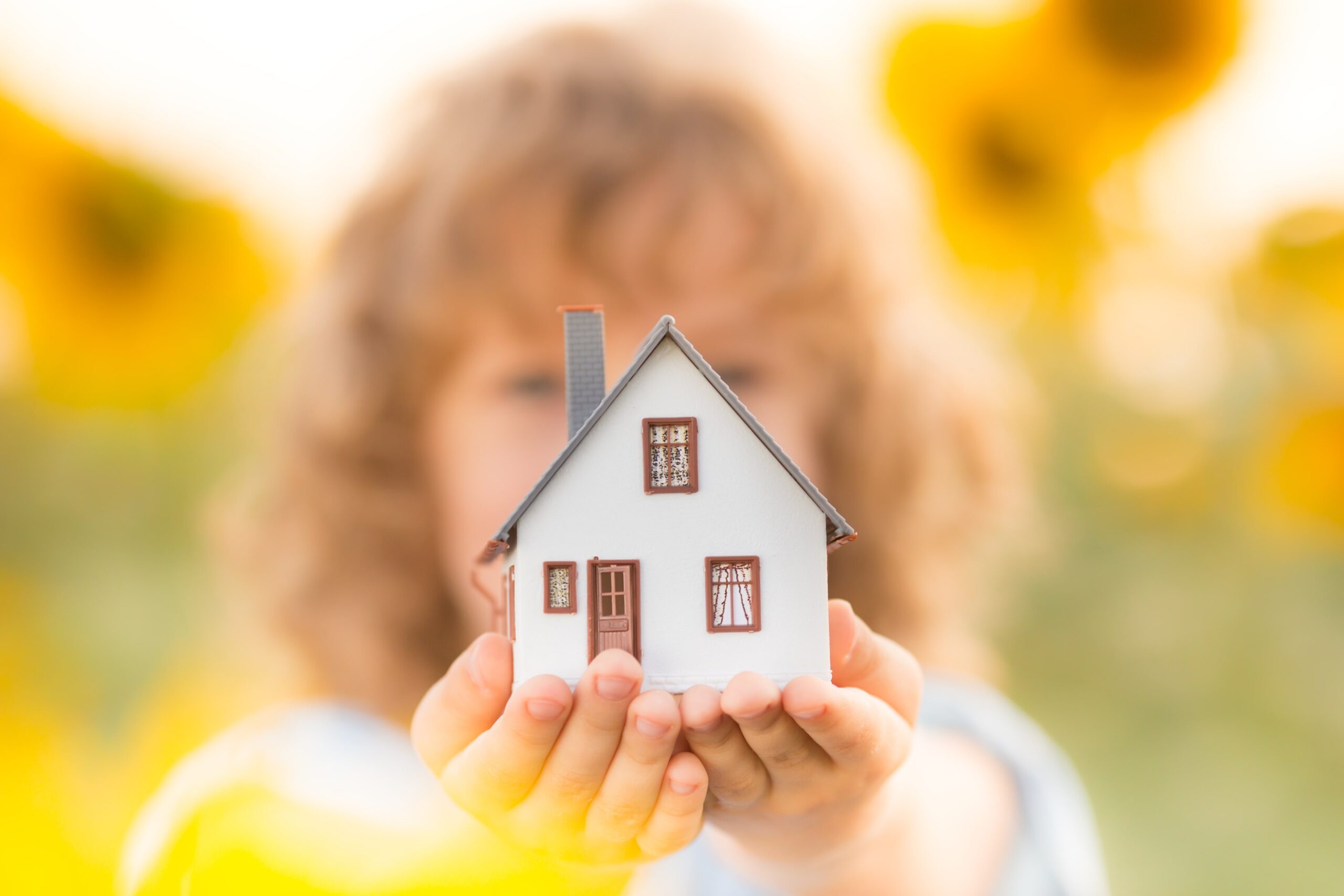 small white house figure in the hand of a child.