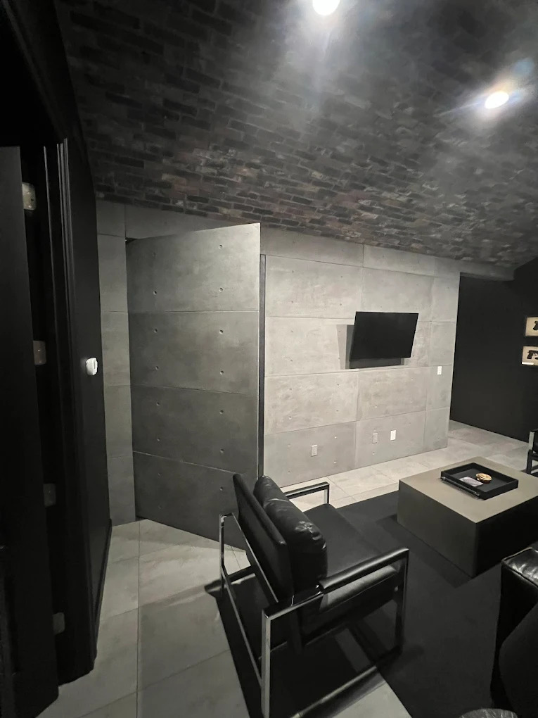 Modern hidden concrete door in a dark living space, blending seamlessly with the concrete wall when closed and opening into the room.