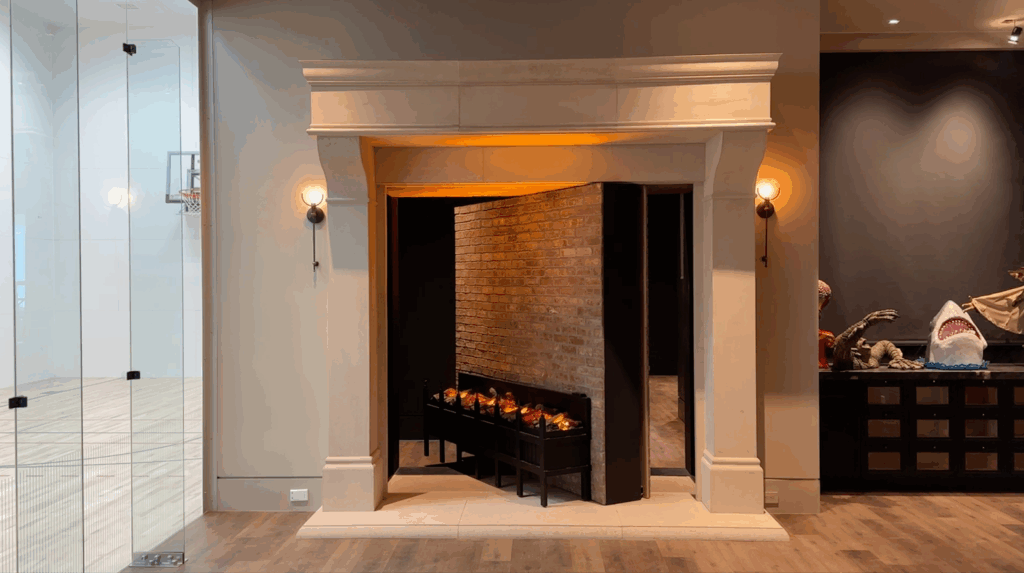 A modern interior with a faux fireplace that conceals a hidden doorway opening into a brick-lined passageway. The fireplace surround and wall sconces disguise the entrance.
