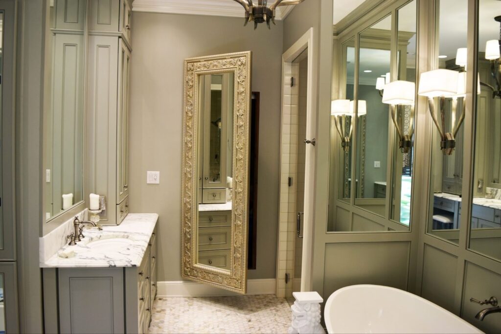 A luxurious bathroom with marble countertops and a freestanding bathtub. A ornate mirror conceals a custom hidden door that blends seamlessly into the wall.