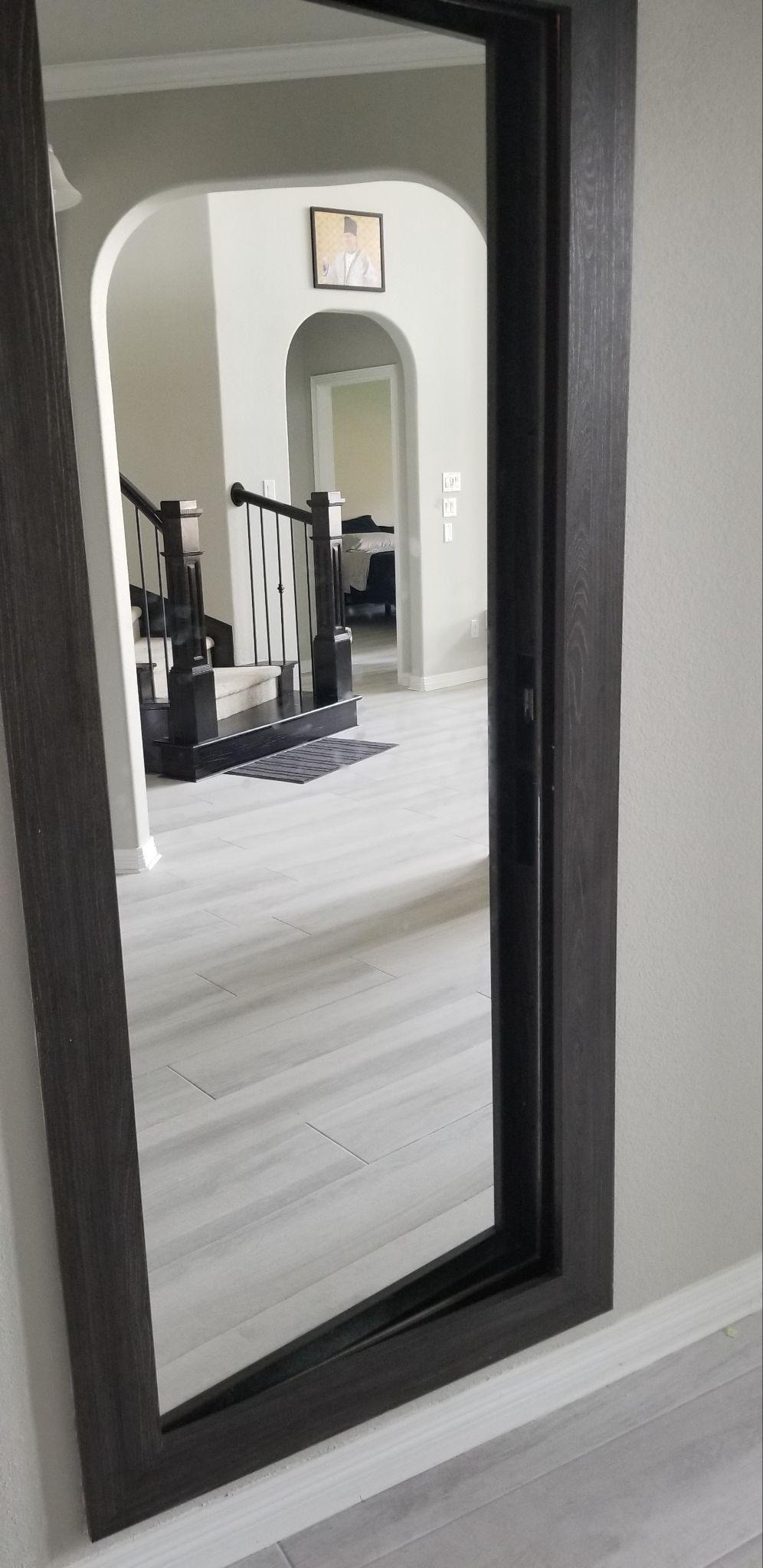 Full-length mirror hidden door with dark wood frame in a modern home.